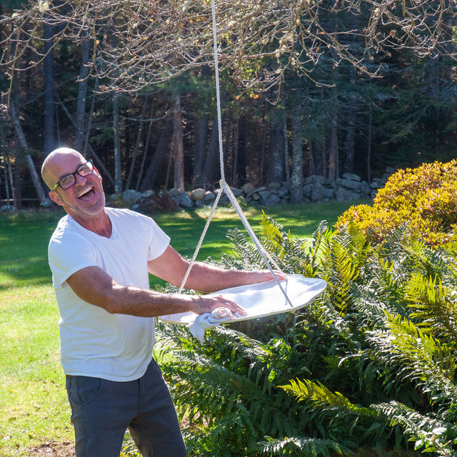 Peter Souza Jr. wiping a white ceramic hanging bird bath clean with a cloth, J Schatz