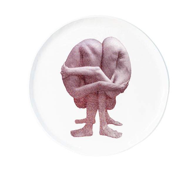 Photographic transfer of a seated figure with knees drawn up and arms wrapped on stoneware Gestures plate, J Schatz.