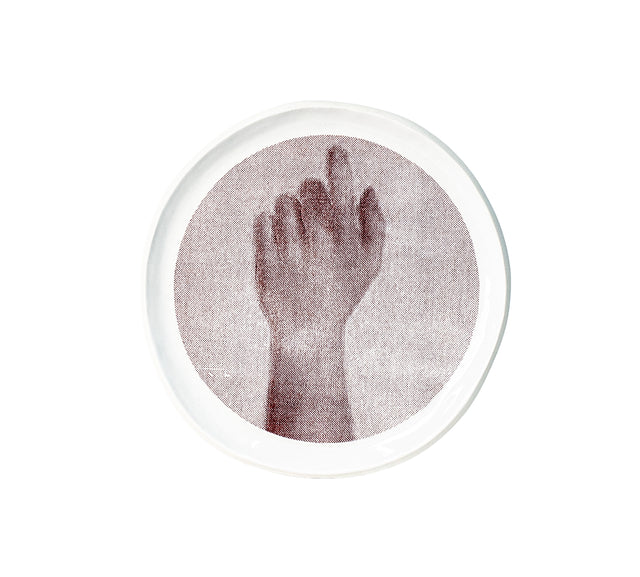 Photographic transfer of a raised forearm and curled hand on stoneware Gestures plate, J Schatz.
