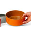 Fire orange ceramic Utilità bowl held to show the glossy interior, J Schatz.
