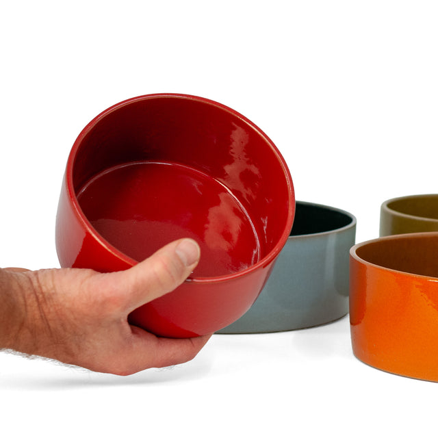 Sumac red ceramic Utilità bowl held to show the glossy interior, J Schatz.